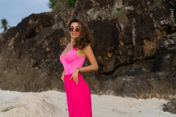 时尚时尚 苗条身材 穿着时髦的粉色裤子 身穿紧身衣 戴着太阳镜 傍晚时分在热带海滩上亮相的年轻女子 — 图库照片