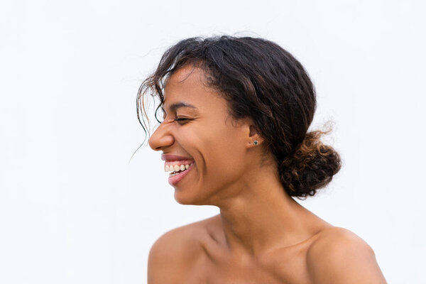 Beauty portrait of young topless african american woman with bare shoulders on white background with perfect skin and natural makeup positive laughing