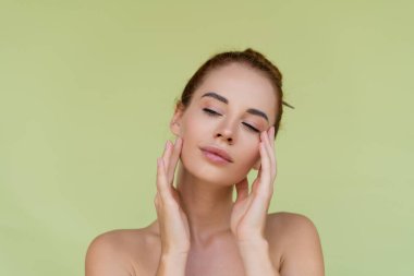 Üstsüz, kızıl saçlı, yeşil omuzlu, mükemmel ciltli ve doğal makyajlı genç bir kadının güzel portresi.