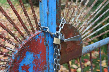 Mavi ve paslı eski kapıların yakın çekimleri zincir ve asma kilitle çevrili. Kilitli kapı. Giriş yasak, yasak bölge