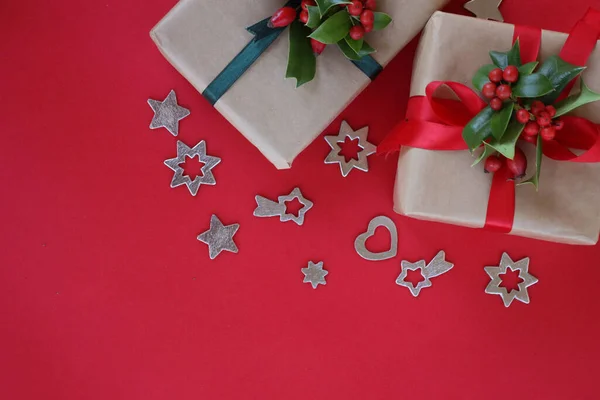 stock image Two Christmas gifts with Holly branch with red berries and silver decorations on a red background with copy space