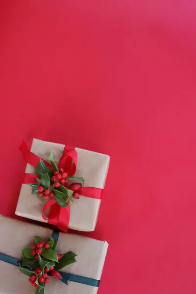 两个圣诞礼物 荷莉枝 红色浆果 红色背景 有复制空间的银质装饰 — 图库照片