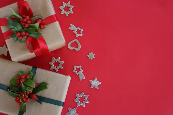 Два Різдвяні Подарунки Філіалом Холлі Червоними Ягодами Срібними Прикрасами Червоному — стокове фото