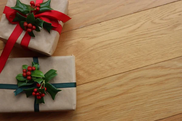 Два Різдвяні Подарунки Прикрасою Холлі Червоними Ягодами Дерев Яному Фоні — стокове фото
