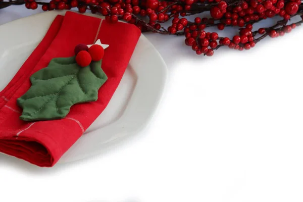 전통적 크리스마스 식탁에 세라믹 접시가 배경에 홀리의 과빨간 식탁보 — 스톡 사진
