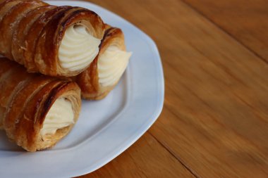 İtalyan geleneksel Cannoli. Tahta masadaki vanilyalı krema ile dolu.