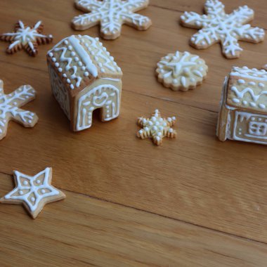 Yıldızlar şeklinde zencefilli kurabiyeler ve ahşap masada kar taneleri olan küçük evler. 