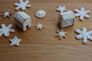 Yıldızlar şeklinde zencefilli kurabiyeler ve ahşap masada kar taneleri olan küçük evler. 