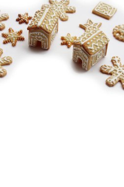 Yıldızlar şeklinde zencefilli kurabiyeler ve beyaz zemin üzerinde izole edilmiş kar taneleri olan küçük evler.