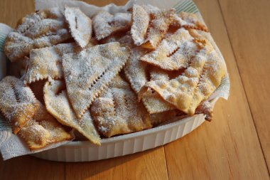 İtalyan Karnaval pastası. Geleneksel karnaval tatlı kıtır börek kızartılmış ve üzerine pudra şekeri serpiştirilmiş. Chiacchere veya crostoli, bugie, sanci beyaz bir tabakta ahşap masada 