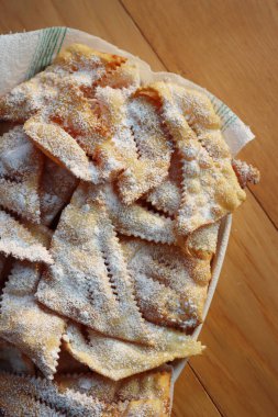 İtalyan Karnaval pastası. Geleneksel karnaval tatlı kıtır börek kızartılmış ve üzerine pudra şekeri serpiştirilmiş. Chiacchere veya crostoli, bugie, sanci beyaz bir tabakta ahşap masada 