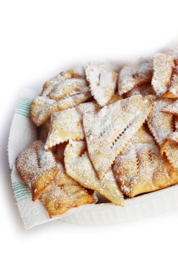 Traditional sweet crisp pastry deep-fried with powdered sugar for Carnival in a white ceramic bowl  on white background. Chiacchere or crostoli, bugie, cenci