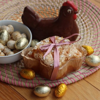 Colomba Pasquale 'de. Koyu çikolatalı tavuk ve folyoya sarılmış yumurtalı Paskalya pastası. İtalyan geleneksel pastası ahşap masada.