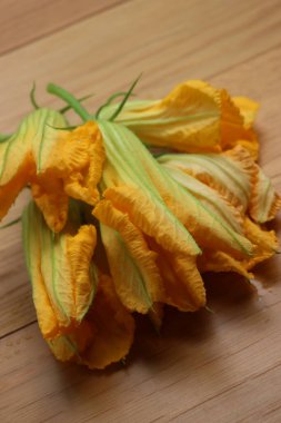 Tahta masada bir demet portakal kabağı çiçeği. Cucurbita çiçekleri