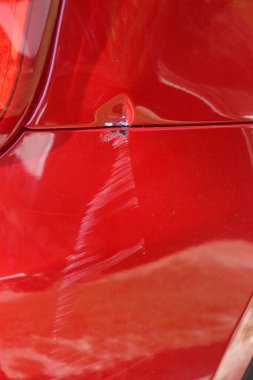 Arka tamponunda hasar olan kırmızı arabanın yakın çekimi.