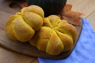 Parlak turuncu balkabağı şekilli ekmek çörekleri ahşap masada taze Delica balkabağıyla