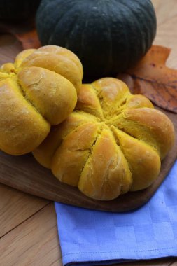 Parlak turuncu balkabağı şekilli ekmek çörekleri ahşap masada taze Delica balkabağıyla