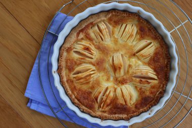 Lezzetli elmalı turta, kremalı ve dilimlenmiş meyveli ahşap masa.