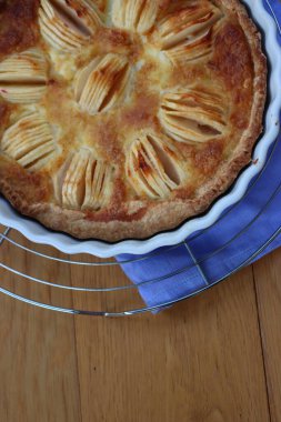 Lezzetli elmalı turta, kremalı ve dilimlenmiş meyveli ahşap masa.