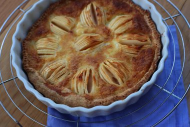 Lezzetli elmalı turta, kremalı ve dilimlenmiş meyveli ahşap masa.