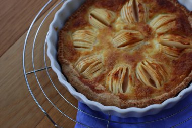 Lezzetli elmalı turta, kremalı ve dilimlenmiş meyveli ahşap masa.