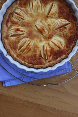 Lezzetli elmalı turta, kremalı ve dilimlenmiş meyveli ahşap masa.