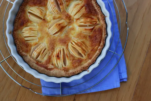 Lezzetli elmalı turta, kremalı ve dilimlenmiş meyveli ahşap masa.