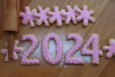 Kısa hamurlu kurabiyeler, 2024 numaralı pembe kalp şeklinde serpiştirilmiş, ahşap masa üzerinde merdane ve kurabiye keskisi