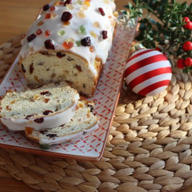 Geleneksel Alman tatlı ekmeğini şekerli meyvelerle dilimledim. Adı da Stollen. Ahşap bir tabakta, Noel süslemeleri ile süslenmiş.