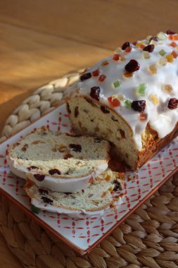 Geleneksel Alman tatlı ekmeğini şekerli meyvelerle dilimledim. Adı da Stollen. Ahşap bir tabakta, Noel süslemeleri ile süslenmiş.