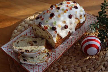 Geleneksel Alman tatlı ekmeğini şekerli meyvelerle dilimledim. Adı da Stollen. Ahşap bir tabakta, Noel süslemeleri ile süslenmiş.