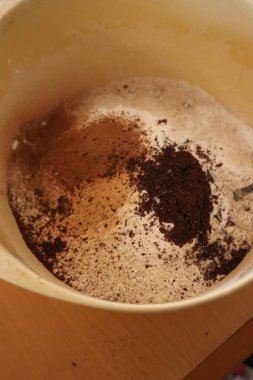 İskandinav spekülasyon kurabiyeleri için kuru malzemelerin karıştırılması: un, tarçın, karanfil ve hindistan cevizi masanın üzerinde plastik bir karıştırma kabında.