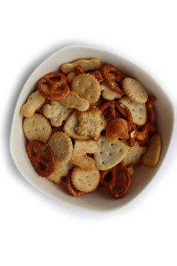 Beyaz bir kasede çeşitli atıştırmalıklar: tuzlu kraker, tohumlu krakerler ve beyaz arka planda izole edilmiş bitki. dağınık parti yemekleri.