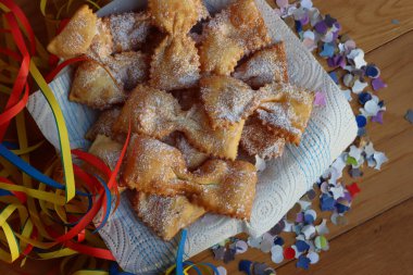 Masadaki tabakta fiyonk şeklinde kızartılmış İtalyan tatlısı. Chiacchere veya crostoli, bugie, cenci konfeti ve kağıt serpentine