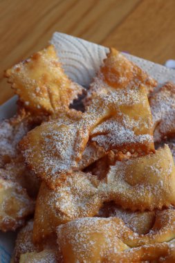 Masadaki tabakta fiyonk şeklinde kızartılmış İtalyan tatlısı. Chiacchere veya crostoli, bugie, cenci konfeti ve kağıt serpentine