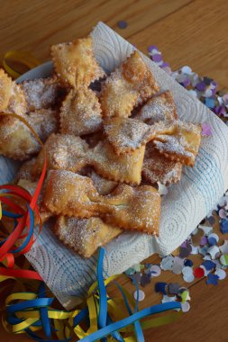 Masadaki tabakta fiyonk şeklinde kızartılmış İtalyan tatlısı. Chiacchere veya crostoli, bugie, cenci konfeti ve kağıt serpentine