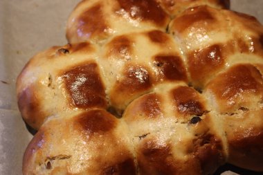 Beyaz parşömen kağıdında yeni pişmiş haçlı çörekler. Geleneksel Paskalya tatlı yemekleri