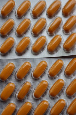 Ahşap masada ilaç kapsülleri var. Su toplamada turuncu haplar