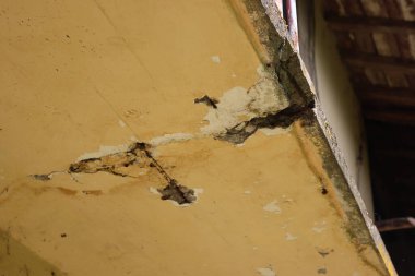 Eski bir evin hasarlı balkonunun alt manzarası. Çatlak betonlu balkon. Balkon tamiri, güçlendirilmiş beton yapıda çatlaklar.