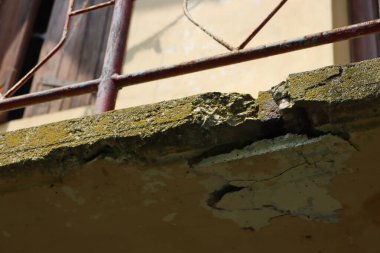 Eski bir evin hasarlı balkonunun alt manzarası. Çatlak betonlu balkon. Balkon tamiri, güçlendirilmiş beton yapıda çatlaklar.