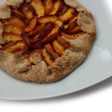 Beyaz arka planda şeftalili ev yapımı galet. Yaz meyveli açık Fransız turtası.