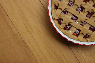 Koyu incirli tart, beyaz seramik kek tepsisi içinde, ahşap masada pişirilmeye hazır. 