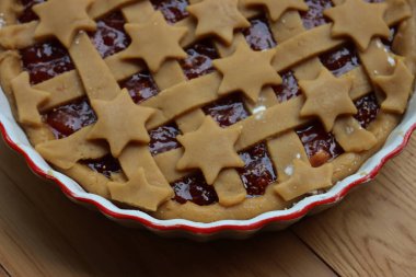 Koyu incirli tart, beyaz seramik kek tepsisi içinde, ahşap masada pişirilmeye hazır. 