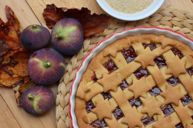 Üzerinde siyah incir reçeli olan turtanın beyaz seramik kek tepsisi ahşap masada. 