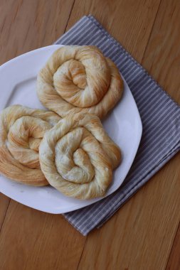 Tahta masadaki tabakta peynirle dolu börekler.