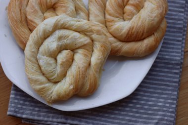 Tahta masadaki tabakta peynirle dolu börekler.