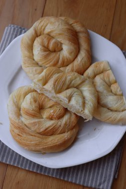 Tahta masadaki tabakta peynirle dolu börekler.