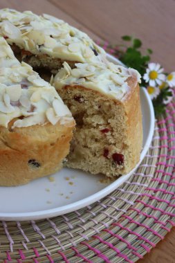 Paskalya için badem ve beyaz çikolata jölesiyle dilimlenmiş tatlı ekmek. Tahta masadaki beyaz tepside kır çiçekleriyle birlikte.