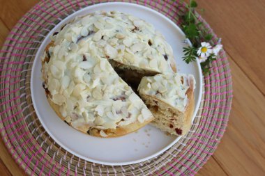 Paskalya için badem ve beyaz çikolata jölesiyle dilimlenmiş tatlı ekmek. Tahta masadaki beyaz tepside kır çiçekleriyle birlikte.