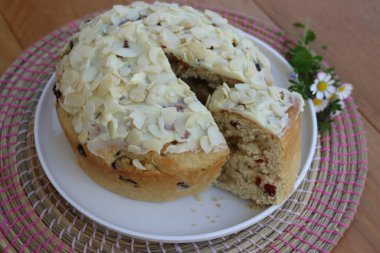 Paskalya için badem ve beyaz çikolata jölesiyle dilimlenmiş tatlı ekmek. Tahta masadaki beyaz tepside kır çiçekleriyle birlikte.